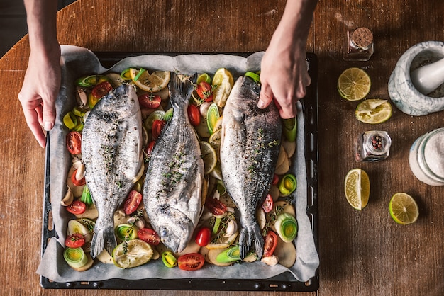 Madre cocina la cena para toda la familia, hornea pescado dorado