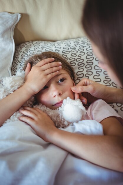 Madre comprobando la temperatura de la hija