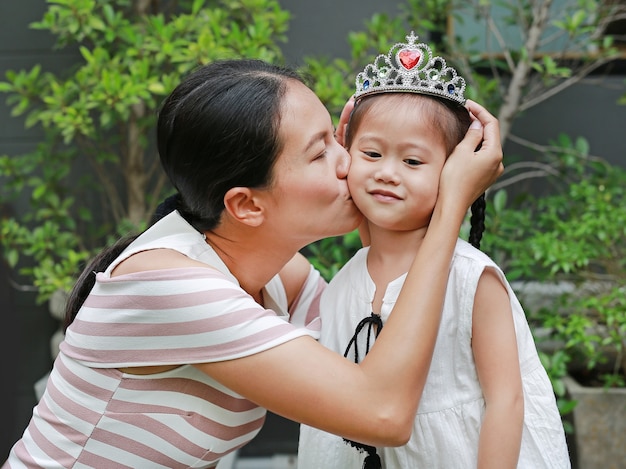 Madre con corona en la cabeza de la niña y besos.