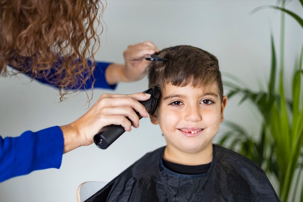 Foto madre cortando el cabello de su hijo en casa