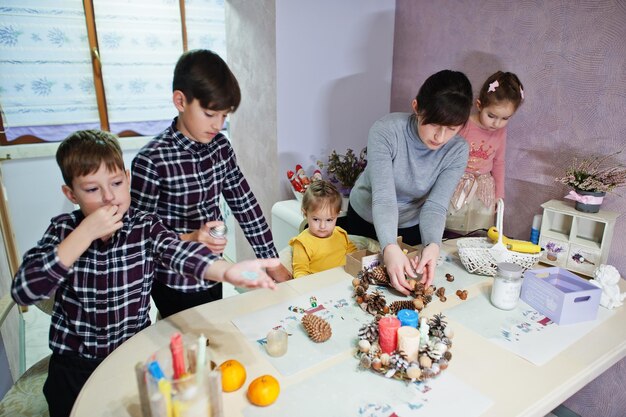 Madre con cuatro hijos hace una corona para la víspera de Navidad y la decoración artesanal. Celebración de Año Nuevo.