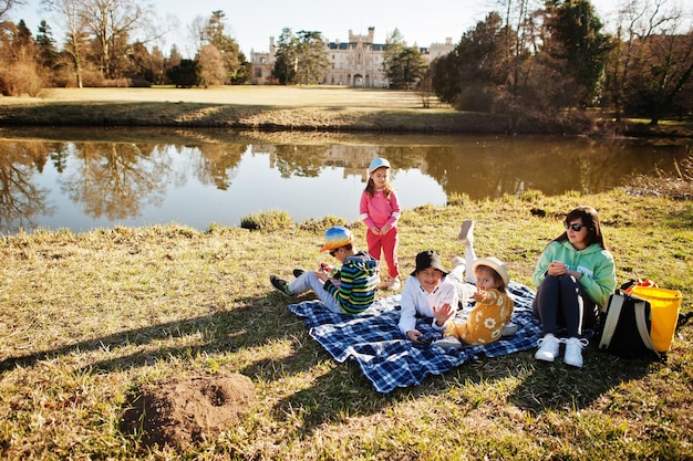 Madre con cuatro hijos haciendo un picnic cerca de la libra en el parque Lednice contra el castillo República Checa