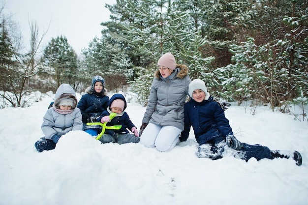 Madre con cuatro hijos en la naturaleza de invierno al aire libre en la nieve