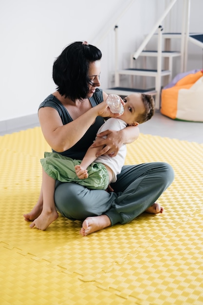 Madre dando agua a un niño discapacitado