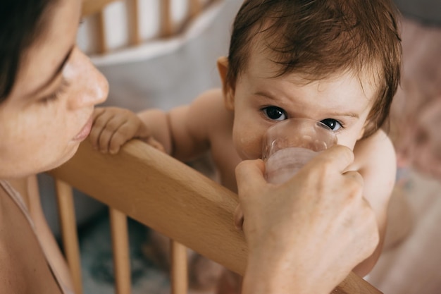 Foto madre dando un vaso de bebida de leche a su bebé cuidado familiar hermosa niña cuidado del bebé