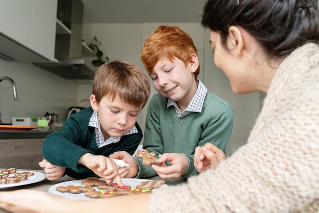 Madre decorando galletas de jengibre con niños en casa