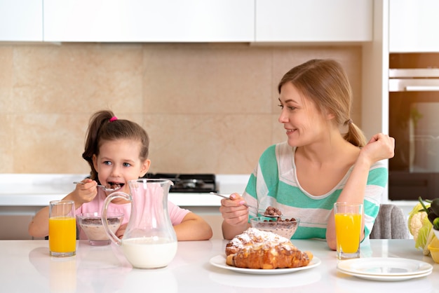 Madre desayunando con su hija en una mesa en la cocina, feliz concepto de madre soltera