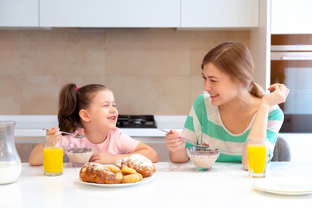 Madre desayunando con su hija en una mesa en la cocina, feliz concepto de madre soltera