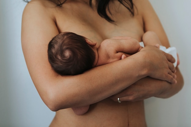 Foto madre desnuda sosteniendo a su bebé infantil