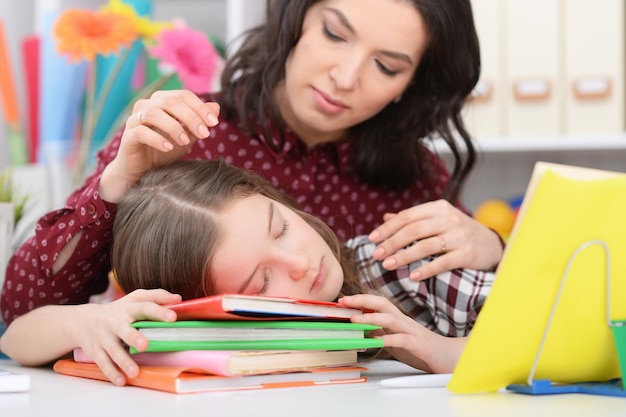 Madre despertando a su hija cansada después de hacer la tarea