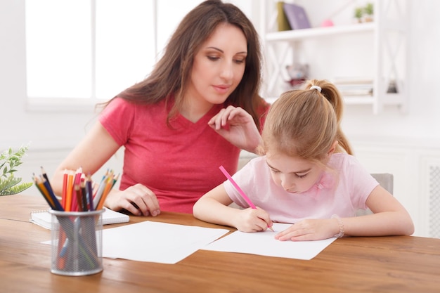 Madre dibujando con su hija en casa. Concepto de maternidad, actividades e intereses conjuntos, calidez materna, educación y desarrollo temprano