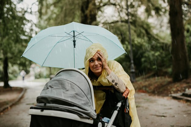 Madre disfrutando al aire libre en el parque con su bebé mientras llueve.