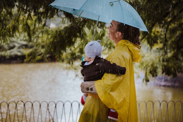 Foto madre disfrutando al aire libre en el parque con su bebé mientras llueve