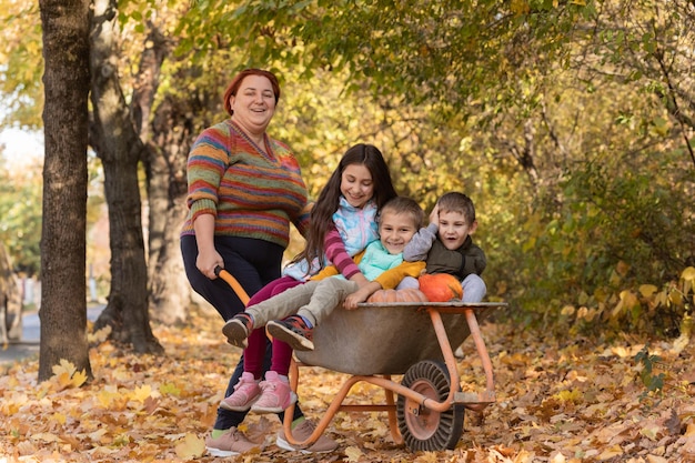 La madre se divierte con los niños y usa una carretilla de jardín con calabazas