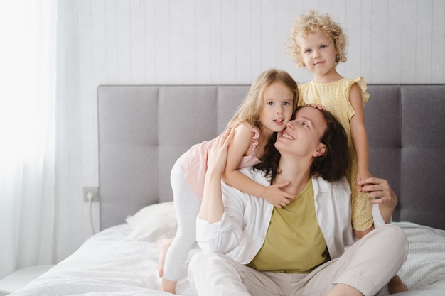 Foto madre divirtiéndose con dos hijas pequeñas en la cama