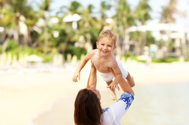 madre divirtiéndose en la playa con su pequeño hijo