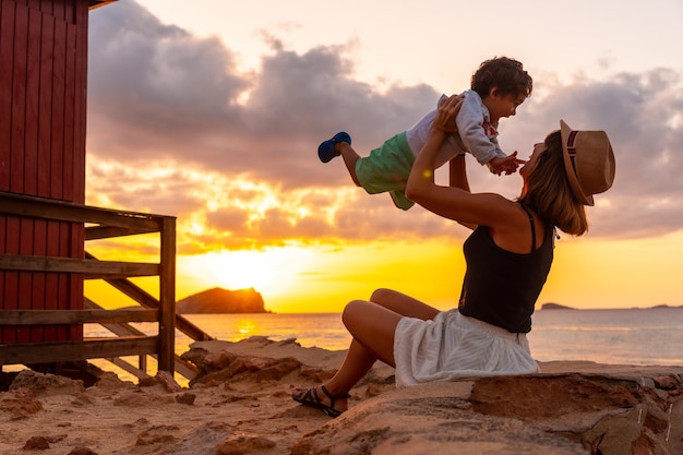 Madre divirtiéndose con su hijo al atardecer en la playa de Cala Comte en la isla de Ibiza Balearic