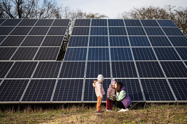 Madre con dos hijas en el fondo de paneles solares Eco energía