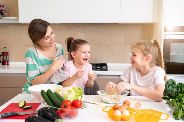 Madre y dos hijas haciendo masa en la cocina y divirtiéndose, concepto de familia feliz y madre soltera