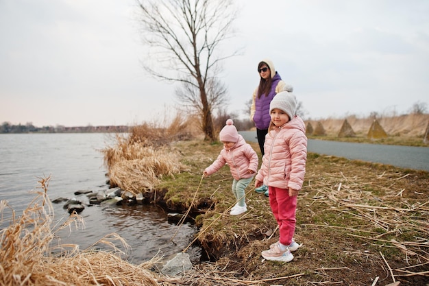 Madre con dos hijas en la orilla del lago.