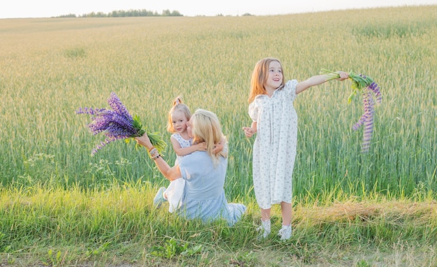 Madre y dos hijas pequeñas para caminar en el campo al atardecer