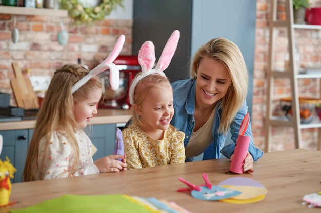 Madre y dos hijas pequeñas jugando con juguetes de Pascua hechos a mano