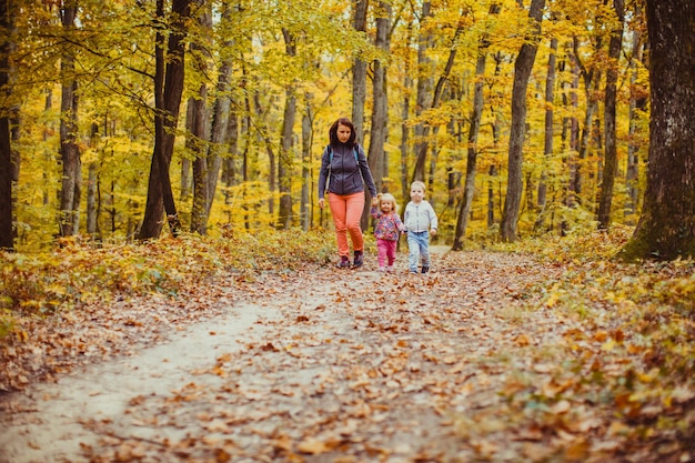 Madre con dos hijos caminando en el bosque otoñal