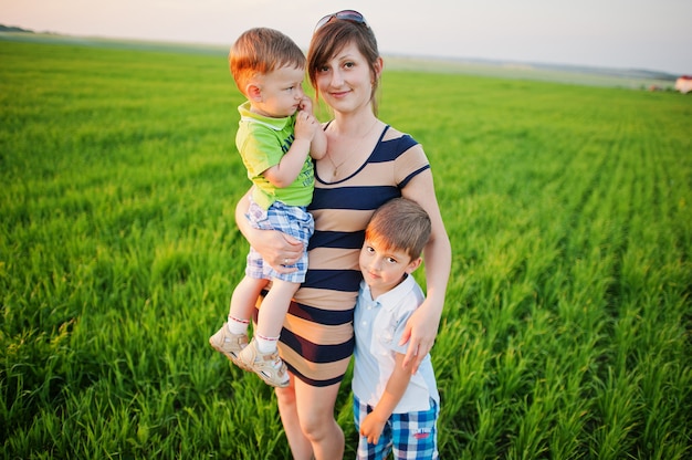 Madre con dos hijos en campo verde.