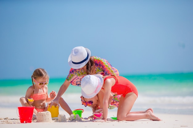 Madre y dos niños jugando con arena en la playa tropical.