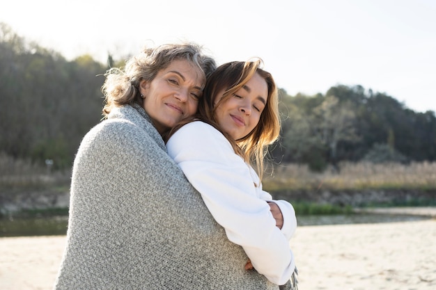 Foto madre e hija abrazándose al aire libre en la playa.