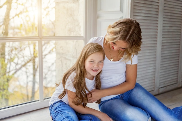 Madre e hija abrazándose cerca de windiow