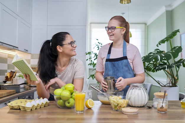 Madre e hija adolescente cocinando pastel de manzana juntos en la cocina de casa