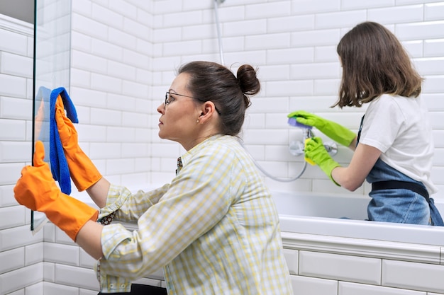 Madre e hija adolescente limpiando juntos en el baño. Niña ayudando a la madre a limpiar en casa. Adolescentes y padres, relaciones, limpieza y limpieza, tareas del hogar