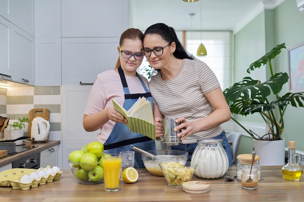 Madre e hija adolescente preparando tarta de manzana en la cocina juntos