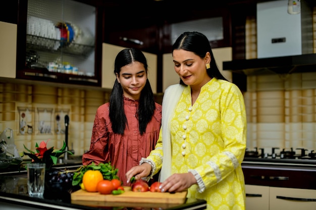Madre e hija adorable cortando manzana en la cocina modelo paquistaní indio