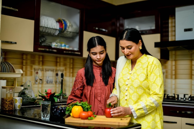 Madre e hija adorable cortando manzana en la cocina modelo paquistaní indio