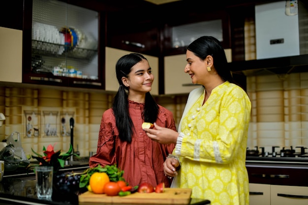 Madre e hija adorable sosteniendo la manzana en la cocina modelo paquistaní indio