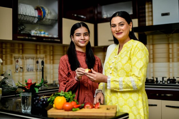 Madre e hija adorable sosteniendo uvas en la cocina modelo paquistaní indio