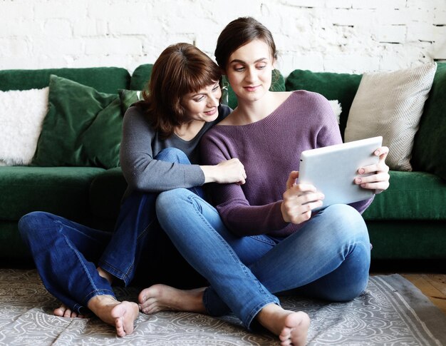 Madre e hija adulta usando una tableta en casa