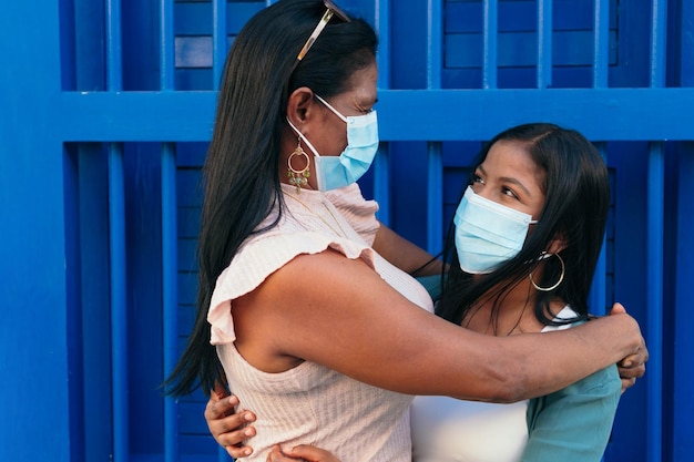 Madre e hija afroamericana en máscara protectora saludándose en la calle durante la pandemia