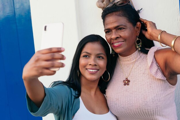 Madre e hija afroamericana tomando una foto con sus teléfonos celulares