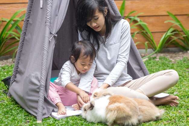 Madre e hija alimentando conejo