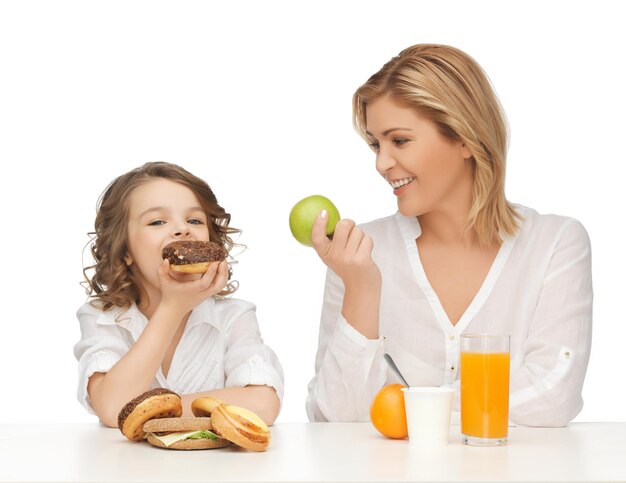 madre e hija con alimentos saludables y no saludables.