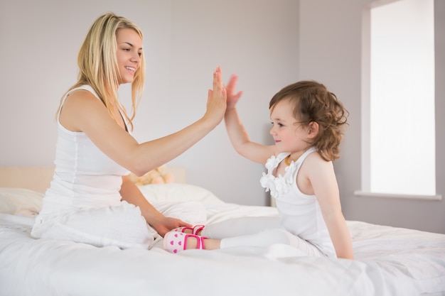 Madre e hija alta fiving en la cama