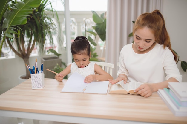 Madre e hija aprendiendo a escribir madre enseñando a la niña la tarea