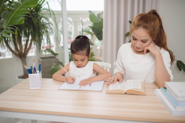 Madre e hija aprendiendo a escribir madre enseñando a la niña la tarea