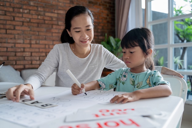 Madre e hija aprendiendo a leer y escribir cartas en casa