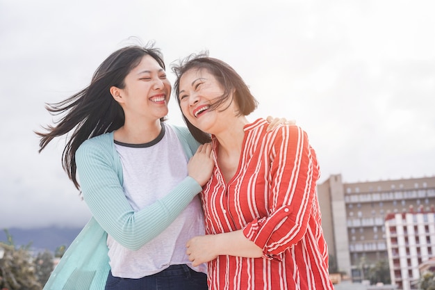 Madre e hija asiáticas divirtiéndose al aire libre - Gente de familia feliz disfrutando del tiempo juntos en la ciudad de Asia