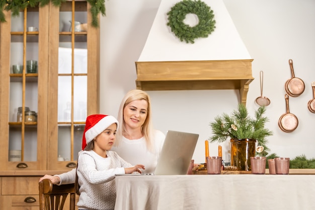 Madre e hija asiáticas que usan la computadora portátil Videollamada Facetime Charlando Comunicación al padre con la decoración del árbol de Navidad en la habitación blanca en casa. Cara sonriente y feliz de celebrar el año nuevo festivel.