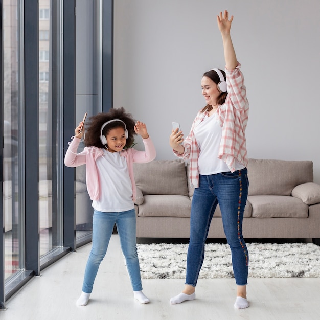 Madre e hija bailando música en casa